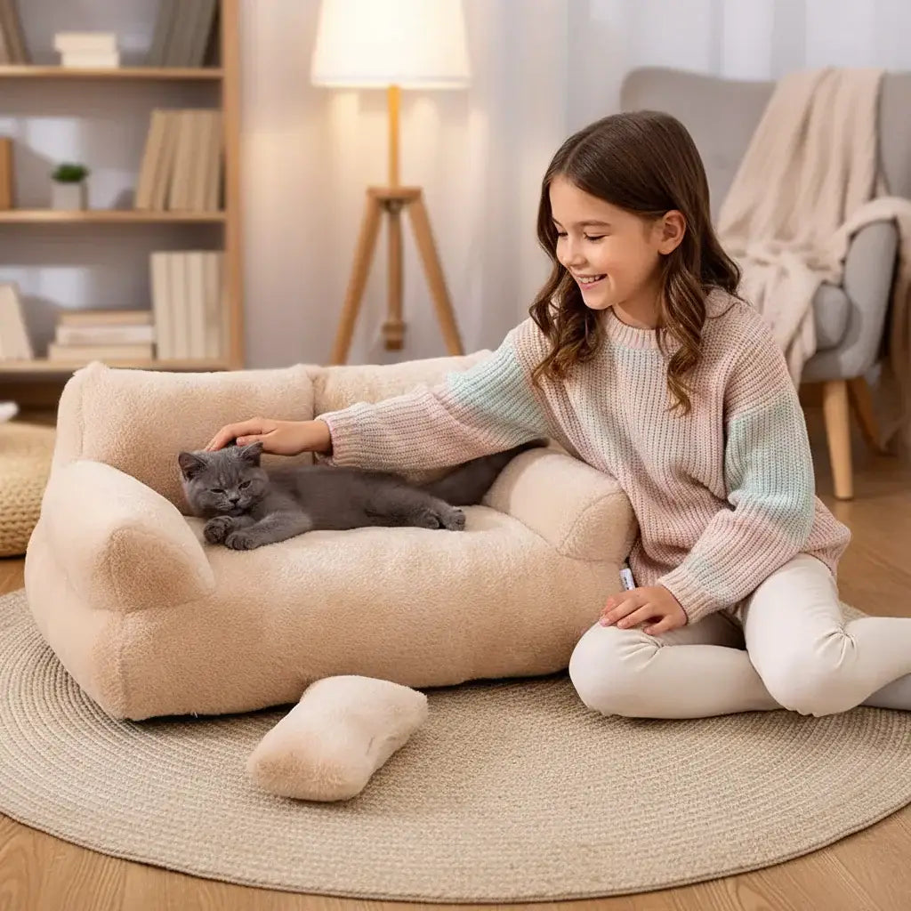 Panier de luxe pour chat avec un chat gris confortablement installé sur un fauteuil en peluche beige.