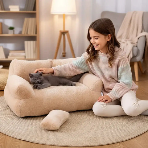 Panier de luxe pour chat avec un chat gris confortablement installé sur un fauteuil en peluche beige.